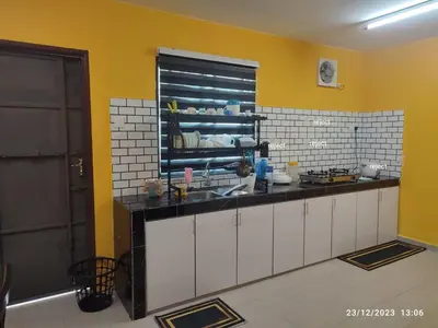 a kitchen with white cabinets and a yellow wall at Zara's Homestay in Kuala Kurau