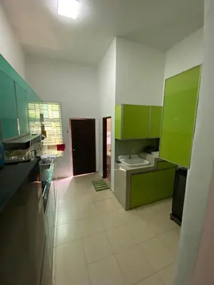 a kitchen with green cabinets and a toilet at Laman Moon Homestay, Melaka in Gua Sai