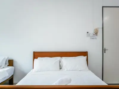 a bed with white sheets and pillows in a room at Lodge 22, 5 min walk to Adventist & Pulau Tikus Market in George Town