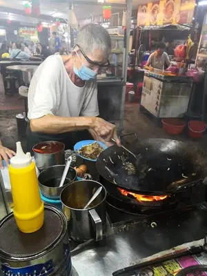 a man cooking food in a wok on a grill at Lodge 22, 5 min walk to Adventist & Pulau Tikus Market in George Town