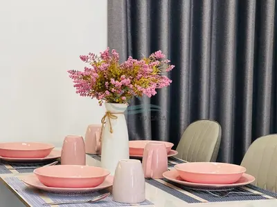 a table with pink plates and a vase of flowers at Venus Suite in Setia Alam 2 in Gua Sai
