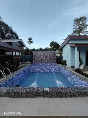 a swimming pool in a yard next to a house at Homestay Teratak D'Desa in Gua Sai