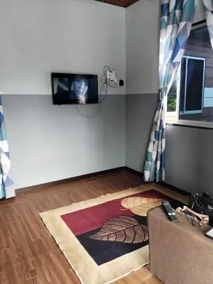 a living room with a couch and a tv on a wall at Homestay Teratak D'Desa in Gua Sai