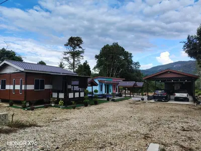 a group of cottages with a car parked in front at Homestay Teratak D'Desa in Gua Sai