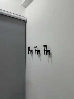 a white wall with three black chairs on it at Modern & Cozy Home Stay in Kampar