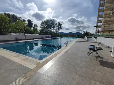 a swimming pool with a table and chairs next to a building at 3B2BR Marina Height Seaview room Rose in Lumut
