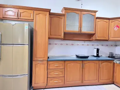 a kitchen with wooden cabinets and a refrigerator at Menglembu Hill Home Stay in Ipoh