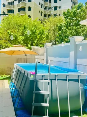 a pool with an umbrella and a stool next to it at Private Pool Villa Near Batu Ferringhi Beach in Batu Ferringhi