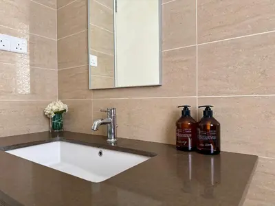 a bathroom sink with two bottles of alcohol on it at By The Sea Batu Ferringhi, Penang Beach in Batu Ferringhi