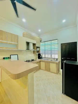 a large kitchen with wooden cabinets and a black refrigerator at Homestay Deedora 87 in Seri Manjung