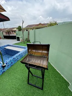 a brown chair sitting on the grass next to a fence at Casa de' Sara Pool Homestay Ipoh in Ipoh