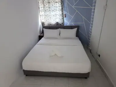 a bed with white sheets in a small room at Cool memories apartment in Tanah Rata