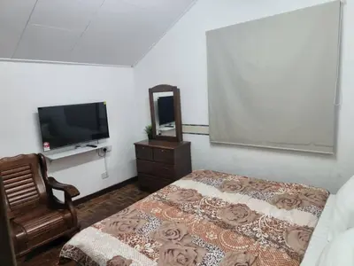 a bedroom with a bed and a dresser and a television at Cool memories apartment in Tanah Rata