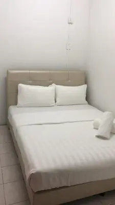 a bed with white sheets and pillows in a room at Cool memories apartment in Tanah Rata