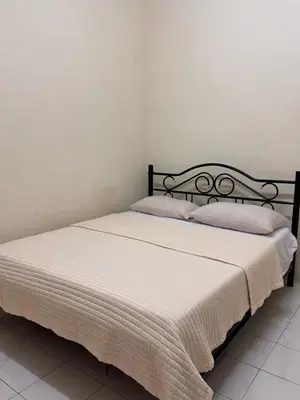 a bedroom with a bed with white sheets and pillows at Teratai Bunda Homestay Tambun in Tambun