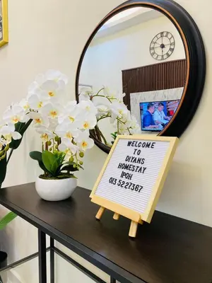 a sign on a table with flowers and a mirror at Diyans Homestay Ipoh in Ipoh