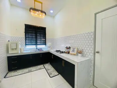 a kitchen with black cabinets and a white counter top at Diyans Homestay Ipoh in Ipoh