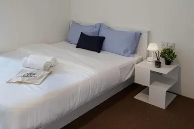 a white bed with blue pillows and a white night stand at A Cozy Place Penang in George Town