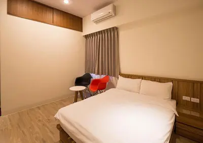 a bedroom with a white bed and a red chair at super hotel in Gua Sai