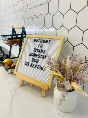 a sign on a table next to a vase of flowers at Diyyans Homestay Ipoh in Ipoh