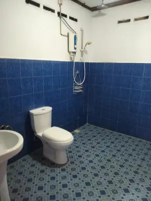 a blue tiled bathroom with a toilet and a shower at Rainbow Villas in Gua Sai