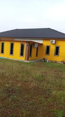 a yellow house with a bench in a field at Homestay Usrati in Taiping