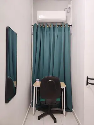 a desk and a chair in a room with green curtains at Dirgahayu Homestay II Nuri in Kulim