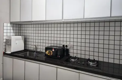 a kitchen with a counter with a microwave and a sink at Dirgahayu Homestay II Nuri in Kulim