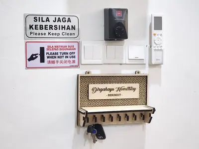 a sign on a wall with a pay phone at Dirgahayu Homestay III Serindit in Kulim