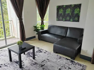 a living room with a black leather couch and a table at Golden hill somersqaure 3 bed room islam apartment in Tanah Rata