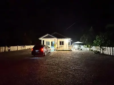 a car parked in front of a small house at night at Omah Kebun Private Pool in Sungai Besar