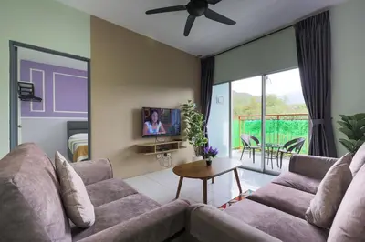 a living room with a couch and a tv at Nice Emerald Avenue suite in Brinchang