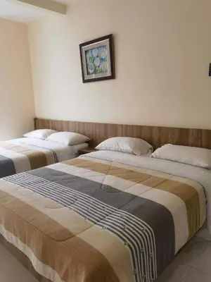 a bedroom with two beds and a picture on the wall at Nice Emerald Avenue suite in Brinchang