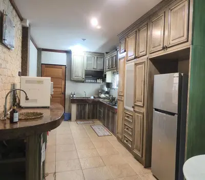 a kitchen with wooden cabinets and a white refrigerator at Untaian Kaseh Villa at Tambun by S&S Groups Consultant in Ipoh