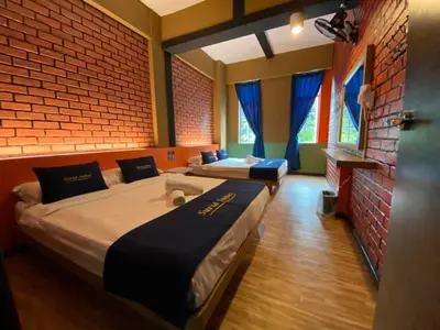 two beds in a room with a brick wall at Suria Suites Apartment & Guesthouse in Tanah Rata