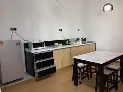 a kitchen with a table and a microwave and a refrigerator at Suria Suites Apartment & Guesthouse in Tanah Rata