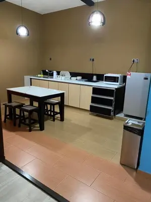 a kitchen with a table and chairs and a refrigerator at Suria Suites Apartment & Guesthouse in Tanah Rata