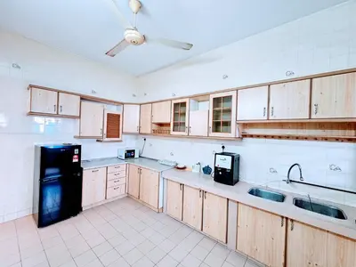 a kitchen with wooden cabinets and a black refrigerator at EasyStay Hostel in Ipoh
