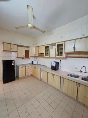 a large kitchen with wooden cabinets and a ceiling fan at EasyStay Hostel in Ipoh