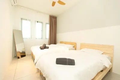 two beds in a room with white walls and windows at Meritus Residensi Seaview Pent Hauz 3BR 10Pax in Perai