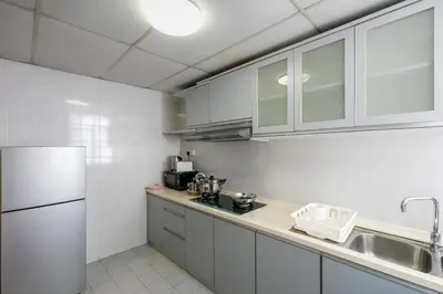 a kitchen with white cabinets and a sink and a refrigerator at 3-Bedroom Stay at Macalister Road & Georgetown, Noble Villa Penang in George Town