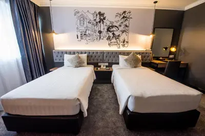 a hotel room with two beds and a desk at Merchant Hotel in George Town
