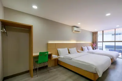 a bedroom with two beds and a desk with a green chair at Gaia Realty Homestay, Private & Convenient Stay in Georgetown in George Town