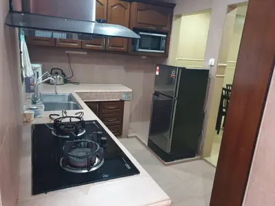 a kitchen with a black stove and a refrigerator at Kinrara HomeStay right at the Heart of Puchong in Gua Sai