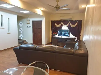 a living room with a leather couch and a television at Kinrara HomeStay right at the Heart of Puchong in Gua Sai