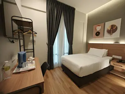 a hotel room with a bed and a table and a desk at Karasky Hotel in Simpang Ampat