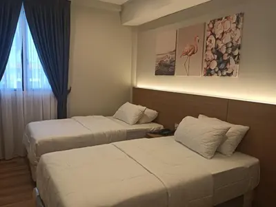 a hotel room with two beds and a window at Karasky Hotel in Simpang Ampat