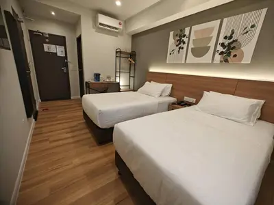 a hotel room with two beds and a door at Karasky Hotel in Simpang Ampat