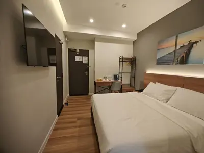 a bedroom with a large white bed and a desk at Karasky Hotel in Simpang Ampat