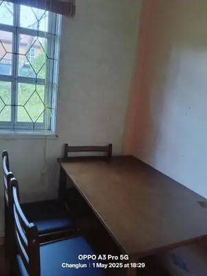 a table and a chair in a room with a window at Zarif homestay in Gua Sai
